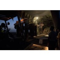 Des soldats du détachement de transit interarmées (DéTIA) déchargent du fret depuis la tranche arrière d'un avion Hercules C-130J-30 de l'US Air Force sur l'aérodrome de Gao, au Mali.