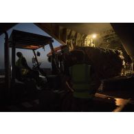Des soldats du détachement de transit interarmées (DéTIA) déchargent du fret depuis la tranche arrière d'un avion Hercules C-130J-30 de l'US Air Force sur l'aérodrome de Gao, au Mali.
