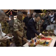 Le président de la République Emmanuel Macron découpe son gâteau d'anniversaire auprès des soldats à Niamey, au Niger.