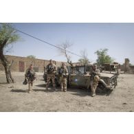 Portrait de soldats du régiment de marche du Tchad (RMT) devant l'épave d'un véhicule militaire dans la cour d'une caserne désaffectée des forces armées maliennes (FAMa) à Bitagoungou, au Mali.