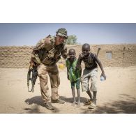 Un soldat du régiment de marche du Tchad (RMT) pose aux côtés d'enfants à Bitagoungou, au Mali.