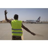 Un soldat du détachement de transit interarmées (DéTIA) guide le roulage d'un avion Falcon 2000 sur la base aérienne de Niamey, au Niger.