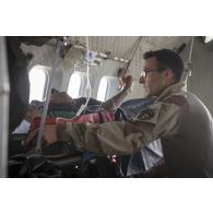 Un élément de la 4e antenne chirurgicale aérotransportable (ACP) veille sur un blessé à bord d'un avion Casa Nurse sur la base aérienne de Niamey, au Niger.