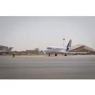Un soldat du détachement de transit interarmées (DéTIA) guide le roulage d'un avion Falcon 2000 sur la base aérienne de Niamey, au Niger.