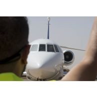 Un soldat du détachement de transit interarmées (DéTIA) guide le roulage d'un avion Falcon 2000 sur la base aérienne de Niamey, au Niger.