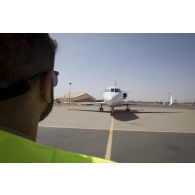 Un soldat du détachement de transit interarmées (DéTIA) guide le roulage d'un avion Falcon 2000 sur la base aérienne de Niamey, au Niger.