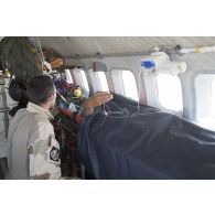 Un élément de la 4e antenne chirurgicale aérotransportable (ACP) veille sur un blessé à bord d'un avion Casa Nurse sur la base aérienne de Niamey, au Niger.