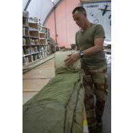 Le brigadier-chef Florian du 1er régiment du train parachutiste (RTP) déroule et surperpose les voiles de parachute pour leur pliage à Niamey, au Niger.