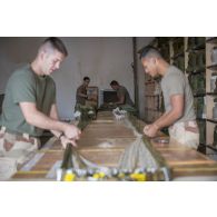 Des soldats du 1er régiment du train parachutiste (RTP) réalisent les ligatures qui permettent la bonne cinématique d'ouverture d'un parachute à Niamey, au Niger.