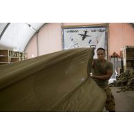 Le brigadier Cyrille du 1er régiment du train parachutiste (RTP) brasse l'ensemble de la voilure d'un parachute afin de contrôler qu'il n'y ait aucune déterioration à Niamey, au Niger.