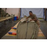Le soldat de 1re classe Romain du 1er régiment du train parachutiste (RTP) met la voilure d'un parachute en position Sapin afin de retrouver le fuseau de référence à Niamey, au Niger.