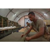 Le soldat de 1re classe Romain du 1er régiment du train parachutiste (RTP) met la voilure d'un parachute en position Portefeuille à Niamey, au Niger.
