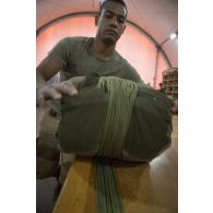 Le soldat de 1re classe Romain du 1er régiment du train parachutiste (RTP) conditionne la voilure et les suspentes d'un parachute pour son pliage à Niamey, au Niger.