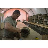 Le brigadier-chef de 1re classe Sébastien du 1er régiment du train parachutiste (RTP) conditionne la voilure et les suspentes d'un parachute pour son pliage à Niamey, au Niger.