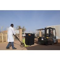 Le caporal-chef Jérôme et l'agent civil Mamadou de l'unité de distribution des produits de santé (UDPS) réceptionnent des médicaments arrivés par voie aérienne à la pharmacie centrale de Niamey, au Niger.