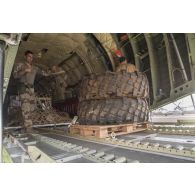 Des soldats du détachement de transit interarmées (DéTIA) chargent des roues à bord d'un avion Transall C-160 à Gao, au Mali.