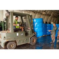 Déchargement de palettes de pneus de la soute d'un avion-cargo de transport Antonov 225 ukrainien par un engin de manutention transpalette OM du RTP (régiment du train parachutiste).