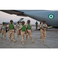 Avion de transport Hercules C-130 de l'armée de l'air nigériane, soute ouverte, sur la piste de l'aéroport. Débarquement de militaires nigérians. En arrière-plan, un avion-cargo de transport C-17 de l'armée de l'air britannique