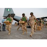 Manutention par des militaires nigérians de caisses de munitions déchargées d'un Hercules C-130 de l'armée de l'air nigériane soute ouverte sur la piste de l'aéroport de Bamako.