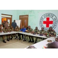 Dans une salle de formation, ornée du drapeau du CICR (comité international de la Croix-Rouge), des stagiaires du Bénin et du Sénégal disposent d'un manuel d'instruction (édité par l'état-major des Armées de la république du Mali et le CICR), en présence d'un capitaine français, officier de liaison de la coopération opérationnelle régionale.