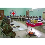Dans une salle de formation, ornée du drapeau du CICR (comité international de la Croix-Rouge), des stagiaires béninois et sénégalais écoutent le cours dispensé à l'aide d'un rétroprojecteur.