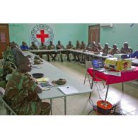 Dans une salle de formation, ornée du drapeau du CICR (comité international de la Croix-Rouge), des stagiaires béninois et sénégalais écoutent le cours dispensé à l'aide d'un rétroprojecteur.