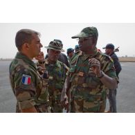 Un capitaine français, officier de liaison de la coopération opérationnelle régionale, discute avec le colonel togolais K. Karka en présence d'un lieutenant togolais sur l'aéroport de Bamako.