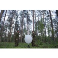 Des artilleurs canadiens gonflent un ballon sonde pour un relevé météorologique au camp de Pabradé, en Lituanie.