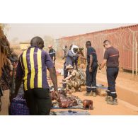 Des soldats achètent des articles sur un marché établi devant l'entrée de la zone vie du détachement Air de la base aérienne de Niamey, au Niger.