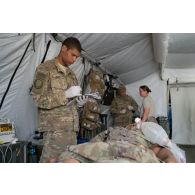 Personnel médical du 250e FST (forward surgical team ou équipe chirurgicale de campagne) examinant un soldat blessé, dans le cadre d'un exercice MASCAL (mass casualties ou afflux de blessés) entrepris conjointement avec les forces françaises et américaines présentes sur le camp militaire de la ville irakienne d'Al-Qaïm, située à proximité de la frontière avec la Syrie.