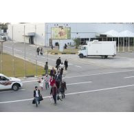 Des ressortissants évacués se dirigent vers leur avion pour l'embarquement sur l'aéroport de Tripoli (Libye), passant près d'une affiche représentant le colonel Kadhafi.
