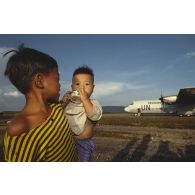 Les enfants cambodgiens saluent les soldats français qui embarquent à bord d'un Hercule C-130.
