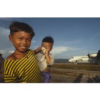 Les enfants cambodgiens saluent les soldats français qui embarquent à bord d'un Hercule C-130.