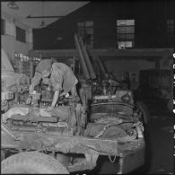 Homme travaillant sur le moteur d'un Wrecker 4 T dans un atelier de la 11e CMRM (compagnie moyenne de réparation du matériel).