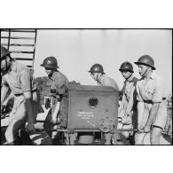 Des artilleurs d'une unité des FTA (forces terrestres antiaériennes) du CEF (corps expéditionnaire français) transportent un système de visée et de de mesure d'un canon de DCA  (défense contre avions).