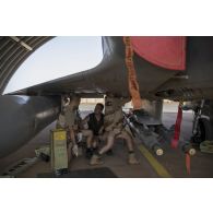 Des techniciens mènent une visite technique auprès des bombes GB-12 Paveway d'un avion Mirage 2000C au sein d'un hangar de la base de Niamey.