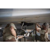 Des techniciens mènent une visite technique auprès d'un avion Mirage 2000C au sein d'un hangar de la base de Niamey.