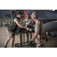 Des techniciens mènent une visite technique auprès du canon DEFA de 30 mm d'un avion Mirage 2000C au sein d'un hangar de la base de Niamey.