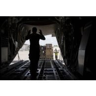 Un élément du 1er RTP guide l'embarquement de fret à bord de la soute d'un avion cargo Hercules C-130.