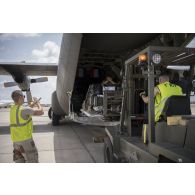 Des élément du 1er RTP dirigent un engin de levage lors d'un chargement de fret à bord d'un avion cargo Hercules C-130 sur l'aéroport de N'Djamena.