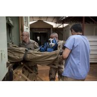 Des éléments du Rôle 2 aident au débarquement d'un brancard depuis une ambulance lors d'un exercice d'évacuation sanitaire à Gao.