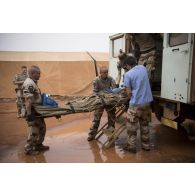 Des éléments du Rôle 2 aident au débarquement d'un brancard depuis une ambulance lors d'un exercice d'évacuation sanitaire à Gao.
