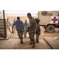 Des éléments du Rôle 2 transfèrent un brancard depuis une ambulance lors d'un exercice d'évacuation sanitaire à Gao.