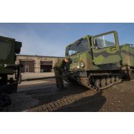 Un soldat estonien encadre le chargement d'un véhicule articulé chenillé (VAC) Bandvagn 206 à bord d'un camion porteur polyvalent logistique (PPLOG) à Jõhvi, en Estonie.