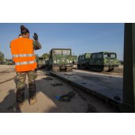 Un soldat guide le chargement de véhicules articulés chenillés (VAC) Bandvagn 206 à bord de camions porteurs polyvalents logistiques (PPLOG) à Jõhvi, en Estonie.