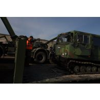Un soldat guide le chargement d'un véhicule articulé chenillé (VAC) Bandvagn 206 à bord d'un camion porteur polyvalent logistique (PPLOG) à Jõhvi, en Estonie.