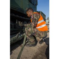 Un soldat fixe les chenilles d'un véhicule articulé chenillé (VAC) Bandvagn 206 à la plateforme d'un camion porteur polyvalent logistique (PPLOG) à Jõhvi, en Estonie.