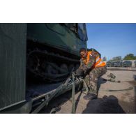 Un soldat fixe les chenilles d'un véhicule articulé chenillé (VAC) Bandvagn 206 à la plateforme d'un camion porteur polyvalent logistique (PPLOG) à Jõhvi, en Estonie.