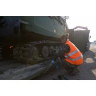 Un soldat fixe les chenilles d'un véhicule articulé chenillé (VAC) Bandvagn 206 à la plateforme d'un camion porteur polyvalent logistique (PPLOG) à Jõhvi, en Estonie.
