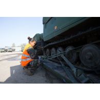 Un soldat fixe les chenilles d'un véhicule articulé chenillé (VAC) Bandvagn 206 à la plateforme d'un camion porteur polyvalent logistique (PPLOG) à Jõhvi, en Estonie.